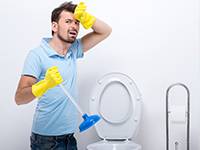 tired homeowner cleaning the toilet at the bathroom